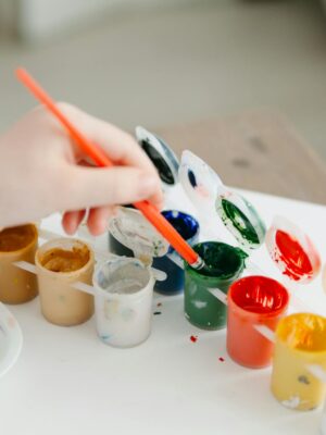 A child paints using a colorful watercolor palette, fostering creativity and fun.