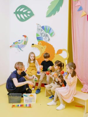 Colorful preschool classroom with teacher and children engaging in activities with toys.